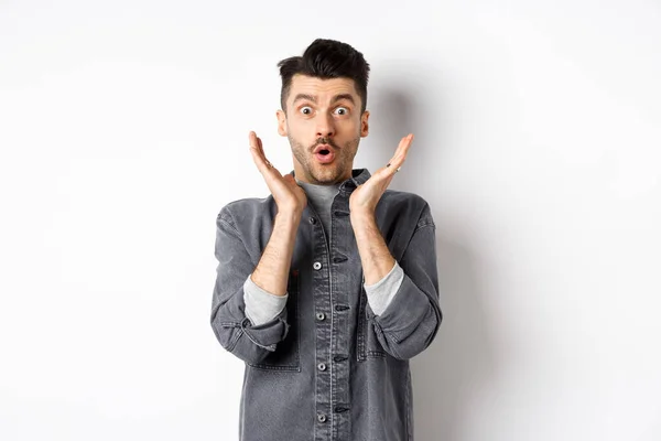 Surprised man gasping excited, say wow and look at amazing advertisement, standing on white background — Stock Photo, Image