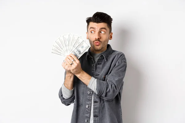 Hombre emocionado abrazando y besando billetes de dólar, sosteniendo el dinero y regocijándose, de pie sobre fondo blanco — Foto de Stock