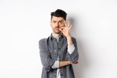 Ciddi adam fermuar hareketi yapıyor, çenesini kapalı tutmasını söyle, kaşlarını çatsın ve dudaklarını mühürlesin, beyaz arka planda dursun.