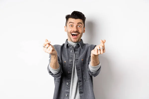 Opgewonden romantische man die handharten toont en lacht naar de camera, liefde en genegenheid uitdrukt, op een witte achtergrond staat — Stockfoto