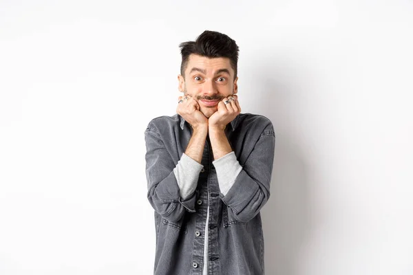 Jovem bonito com bigode sorrindo e olhando sonhador para a câmera, olhando para algo bonito, admirar a verdadeira beleza, de pé sobre fundo branco — Fotografia de Stock