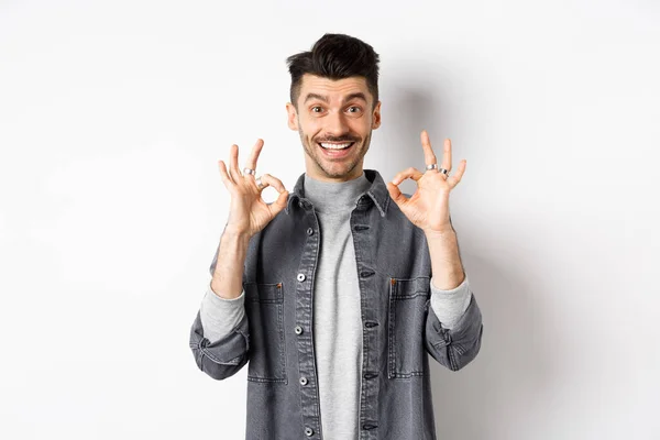 Chico feliz decir que sí, sonriendo y mostrando signos bien, como buen producto, asiente con la cabeza en la aprobación y hacer la cara satisfecha, alabanza excelente trabajo, de pie sobre fondo blanco —  Fotos de Stock