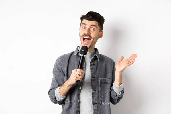 Emocionado chico elegante dando discurso, hablando en micrófono, realizar o cantar karaoke, de pie sobre fondo blanco —  Fotos de Stock