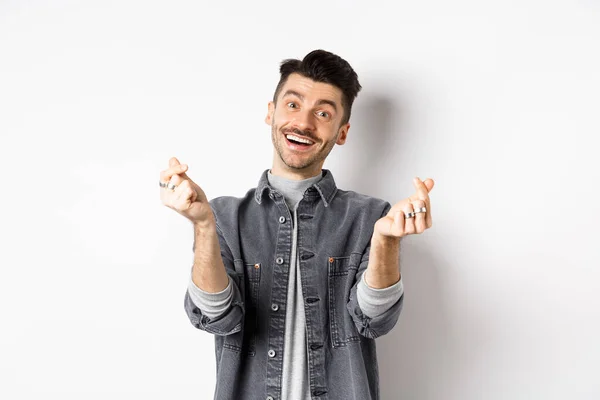 Hombre sonriente guapo mostrando corazones de mano y mirando con amor a la cámara, de pie sobre fondo blanco — Foto de Stock