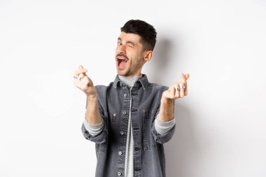 Komik adam göz kırpıyor, el işareti yapıyor, romantik ve mutlu hissediyor, beyaz arka planda duruyor.