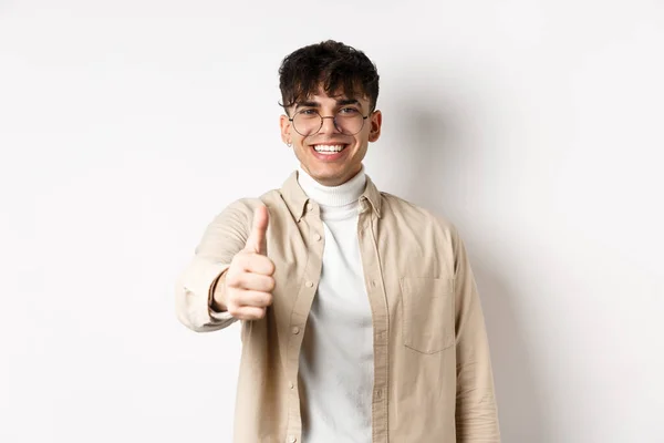 Imagem do jovem feliz mostrando o polegar para cima e sorrindo satisfeito, louvar bom trabalho, dizer bem feito e olhar satisfeito, de pé sobre fundo branco — Fotografia de Stock