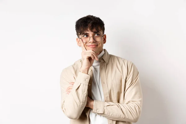 Imagem de um jovem sonhador feliz imaginando algo bom, sorrindo e olhando para o canto superior direito pensativo, em pé sobre fundo branco — Fotografia de Stock