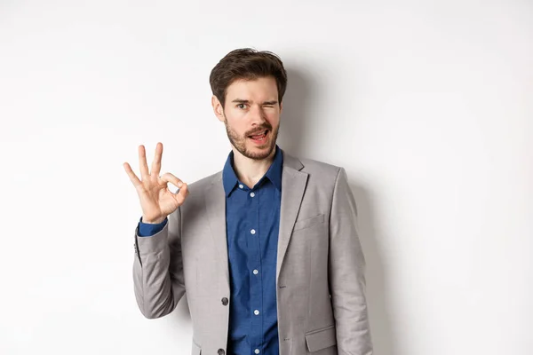 All good. Confident male ceo manager showing okay sign and winking, everything under control, praising nice work, standing on white background — Stock Photo, Image