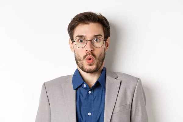 Close up retrato de trabalhador de escritório animado em óculos e terno dizendo uau, olhando espantado para a câmera, de pé contra o fundo branco — Fotografia de Stock
