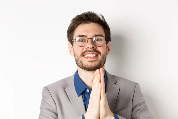 Close-up de feliz cara agradecido em óculos e terno mostrando gratidão, fazer sinal namaste e sorrir, de pé sobre fundo branco — Fotografia de Stock