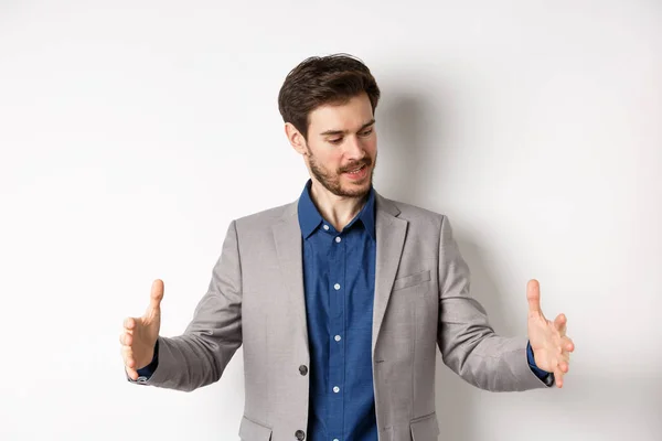 Excited handsome businessman showing long size thing, big object with stretch out hands, standing in suit on white background — Stock Photo, Image