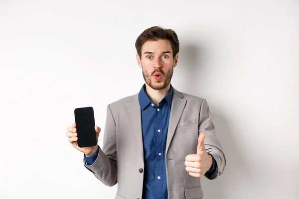 전자 상거래와 온라인 쇼핑 컨셉이야. 흥분 한 사업가는 빈 스마트폰 화면과 엄지, 흰색 배경을 보여 주면서 금융 앱을 추천 한다 — 스톡 사진