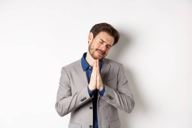 Yalvaran işadamı, el ele tutuşup dua ediyor ve yardım istiyor. Bir şeye ihtiyacın var, lütfen söyle, beyaz arka planda duruyor.