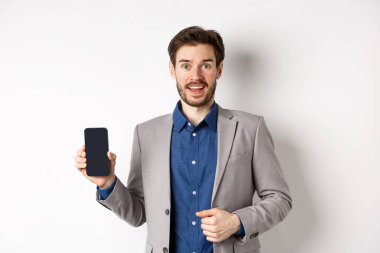 Heyecanlı takım elbiseli iş adamı boş telefon ekranı, gülümseme, online reklam, beyaz arka planda durmak