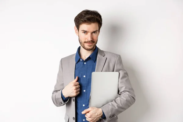 Successful businessman in stylish suit carry laptop and looking confident at camera, smiling pleased, white background — Stock Photo, Image