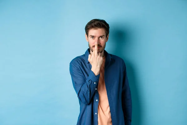 Ignorant and rude guy showing middle finger and smiling, say fuck you, standing on blue background — Foto Stock