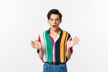 Heyecanlı ve şaşkın yakışıklı adam elini kaldırdı ve kameraya baştan çıkarıcı bir şekilde baktı, bir şey istedi, beyaz arka planda durdu..