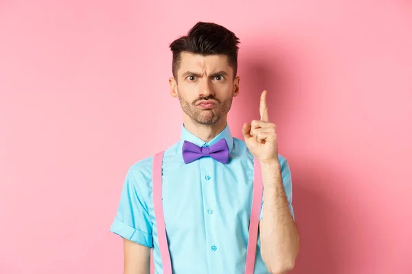Angry male teacher shaking finger and scolding someone who misbehave, frowning grumpy, and teaching lesson, standing over pink background — Stock Photo, Image