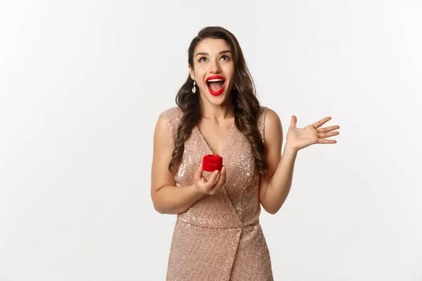 Image of excited woman receiving engagement ring and marriage proposal, scream of joy and happiness, wearing evening dress and red lipstick, standing over white background — Stock Photo, Image