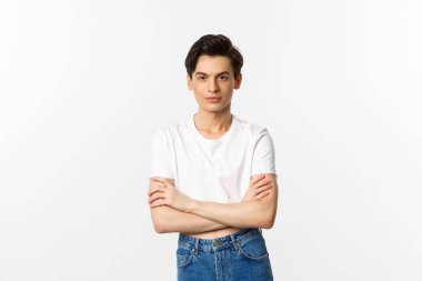 Ekinler içinde sırıtan, kendine güvenen, göğsünde çapraz kollar olan ve beyaz arka planda duran küstah bir gay resmi.