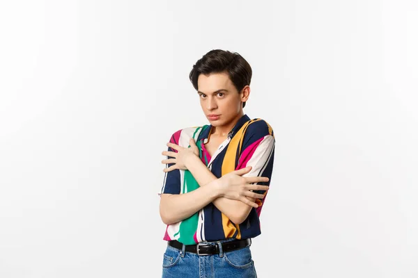 Image of timid gay man cringe and looking displeased at camera, hugging himself defensive, standing over white background — Stock Photo, Image