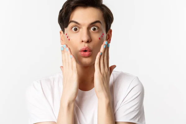 People, lgbtq and beauty concept. Close-up of handsome gay man express surprise, showing hands with blue nail polish, standing over white background — Stock Photo, Image