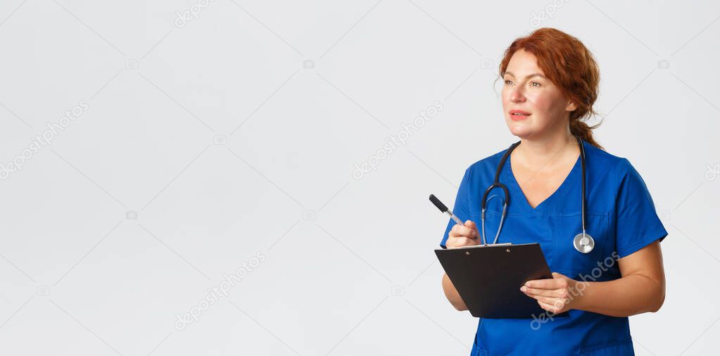 Medicine, healthcare and coronavirus concept. Focused female doctor taking notes, checkup on patient, listening to person complaints in clinic, writing down clipboard, standing in scrubs