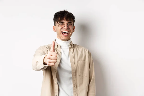 Boa ideia. Jovem feliz rindo e mostrando o polegar para cima, como algo bom, de pé sobre fundo branco, elogiando você — Fotografia de Stock