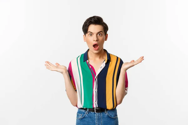Image of surprised young male model staring at camera, spread hands sideways in complete disbelief, standing over white background — Stock Photo, Image