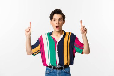 Şaşırmış cinsiyet değişkeni adam parmak kaldırıyor, şaşkın şaşkın bakıyor, müthiş bir promosyon teklifi sunuyor, beyaz arka planda duruyor.