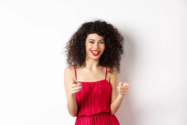 Mulher bonita animado em vestido vermelho parabenizá-lo, apontando os dedos para a câmera e sorrindo, de pé sobre fundo branco — Fotografia de Stock