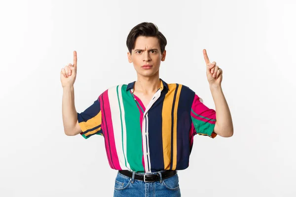 Disappointed and angry man pointing fingers up, showing something bad, standing over white background — Stock Photo, Image