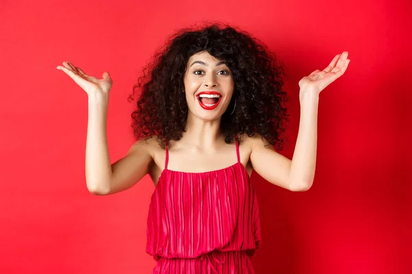 Opgewonden mooie vrouw tillen handen omhoog en schreeuwen van geluk en vreugde, applaus met vreugde, staan op rode achtergrond — Stockfoto