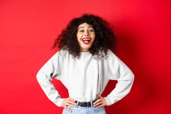 Eccitato donna positiva ridere e sorridere, sentirsi ottimisti, guardando promo divertente, in piedi su sfondo rosso — Foto Stock