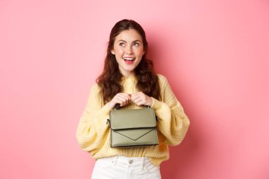 Düşünsene güzel bir kadın gülümsüyor, sol üst köşeye bakıyor, mutlu bir yüz, bir şeyler hayal ediyor, bir fikri var, pembe arka planda duruyor.