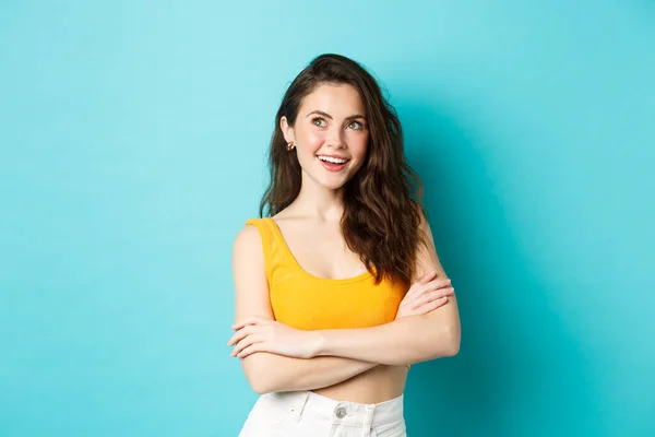 Verão e conceito de estilo de vida. Jovem mulher pensativa cruz braços no peito e olhando para o canto superior esquerdo logotipo banner, planejamento de férias, fundo azul — Fotografia de Stock