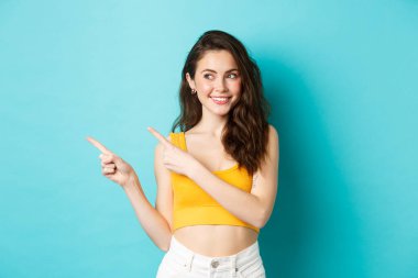 Fotokopi alanında reklam yapan modern bir kadının portresi, logo afişini gösterip sola bakıyor, dişleriyle gülümsüyor, mavi arka planda duruyor.