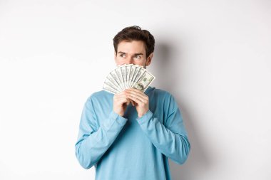 Hayalperest adam mal almayı düşünüyor, elinde para tutuyor ve dalgın dalgın bakıyor, alışveriş yapıyor, beyaz arka planda dikiliyor.