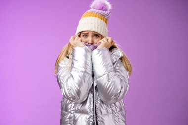 Korkmuş, kendine güveni olmayan, şirin şapkalı, parlak ceketli, kumaş ceketli, korkmuş, kambur bakışlı, korkmuş, korkmuş, korkmuş, ürkek, mor arka planda duran korkak kız.