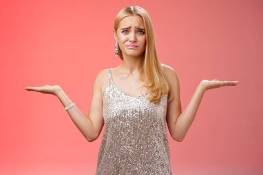 Gergin, kararsız, sevimli sarışın kadın mücadele ediyor, karar veriyor, omuz silkiyor, kaşlarını çatıyor, üzgün, kendine güveni yok, baskı kuramıyor, seçim yapamıyor, hayal kırıklığına uğramış kırmızı arka plan.