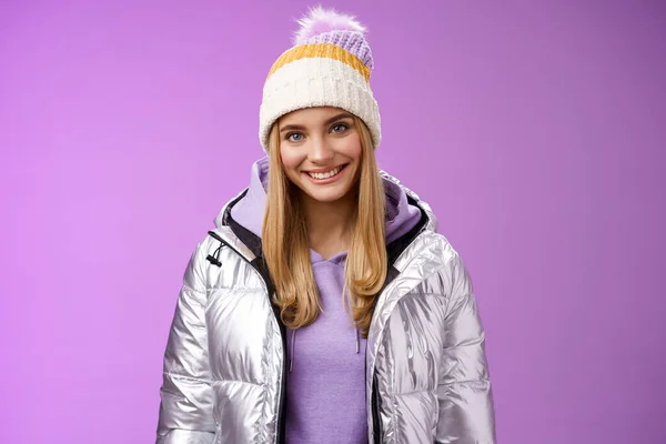 Nette junge blonde europäische Frau trägt warme, gemütliche Jacke Hut Skigebiet Urlaub Spaß lächelnd amüsiert mieten Ausrüstung lernen wollen Snowboard stehen glücklich lila Hintergrund — Stockfoto