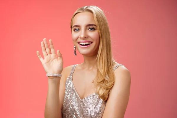 Cintura-up estúdio tiro amigável atraente mulher loira concurso elegante dizer oi acenando levantado mão saudação acolhedor amigo sorrindo encantado apresentando-se oi gesto, fundo vermelho — Fotografia de Stock