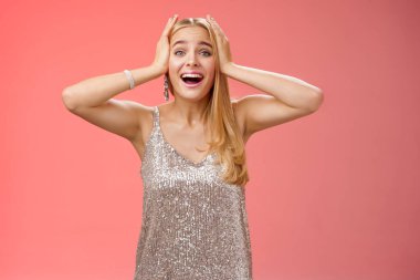 Şaşırmış, heyecanlı, gümüş renkli şık elbiseli sarışın kadın kendi şansına inanamıyor. Mutluluk el ele tutuşuyor. Gülümsüyor, haykırıyor, hayrete düşürüyor.