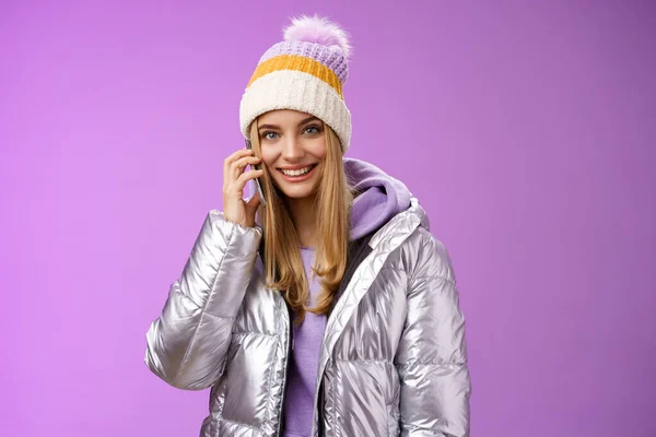 Freudige moderne stylische Millennial junge blonde Mädchen reden Freunde Smartphone ruft Mama aus Winterurlaub im Ausland mit Hut silberne Jacke halten Handy in der Nähe Ohr lächelnd — Stockfoto