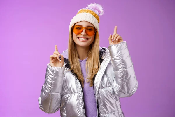 Alegre energizado entretido bonito loiro mulher se divertindo desfrutar de férias nevado montanha viagem usando óculos de sol prata jaqueta chapéu de inverno dançando apontando para cima divertido pé roxo fundo — Fotografia de Stock