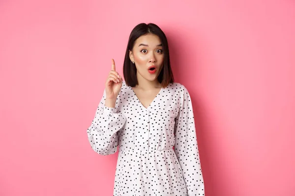 Emocionado chica asiática teniendo una idea, diciendo sugerencia, levantando el dedo y hablando, de pie sobre fondo rosa — Foto de Stock