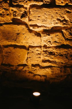 Lekeli taş duvar, pürüzlü desen ve sıcak kehribar parıltısı sergiliyor.,