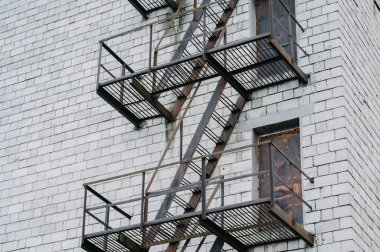 Beyaz Tuğla Cephesi 'nde Metal Yangın Kaçışı, Paslı Platformlar ve Çapraz Dökümlü Merdivenler