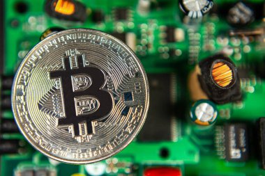 Bitcoin sikkelerinin fotoğrafı bir anakart madencilik madeni paralarının üzerinde renkli bir zemindeki kripto para piyasasını sembolize ediyor.