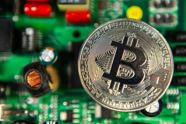 Bitcoin sikkelerinin fotoğrafı bir anakart madencilik madeni paralarının üzerinde renkli bir zemindeki kripto para piyasasını sembolize ediyor.